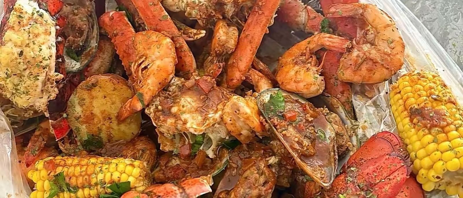 A CCK seafood boil bag with lobster tails, snow crab, king prawns, mussels, corn and potatoes