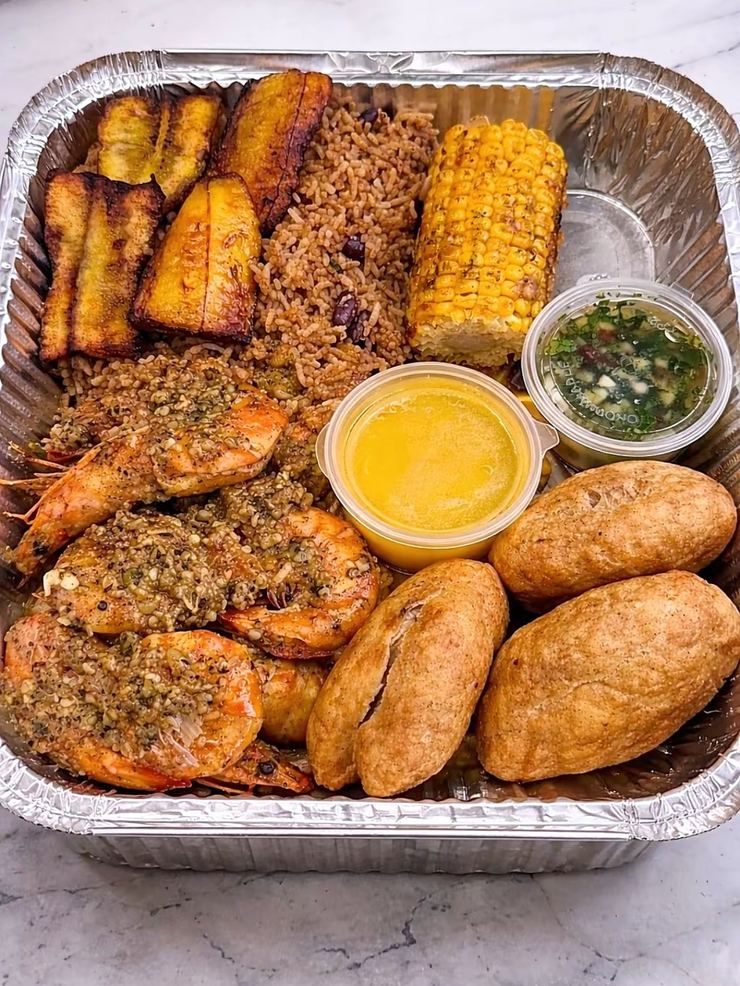 Garlic prawns with plantain, rice and peas, corn and festival in a tray